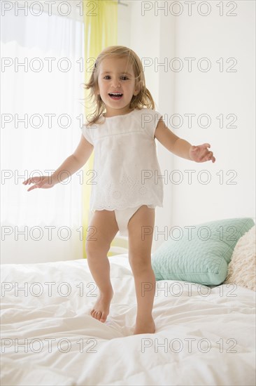 Caucasian girl jumping on bed