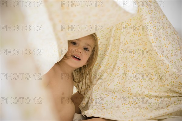 Caucasian girl playing under blankets