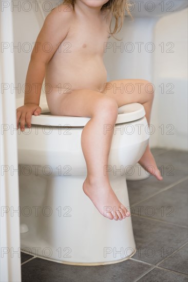 Nude Caucasian girl sitting on toilet