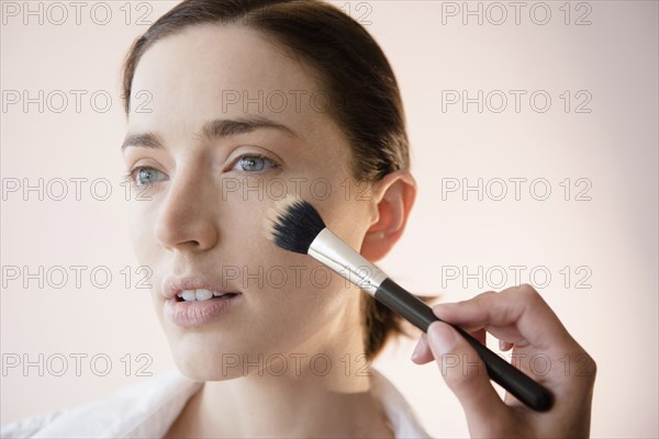 Woman having makeup applied by stylist