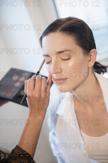 Woman having makeup applied by stylist