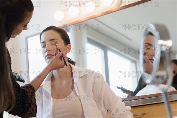 Woman having makeup applied by stylist