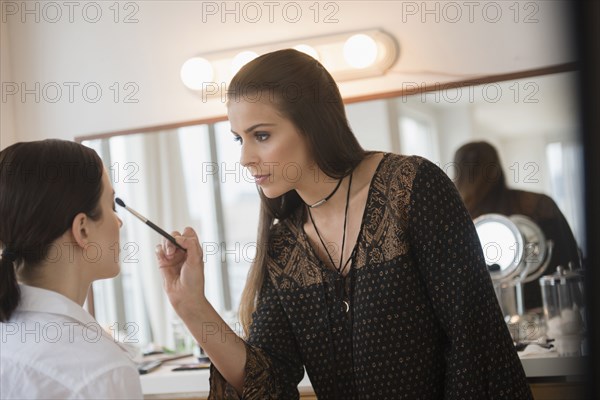 Woman having makeup applied by stylist