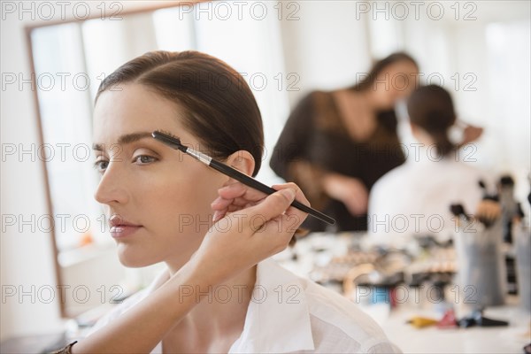 Woman having makeup applied by stylist