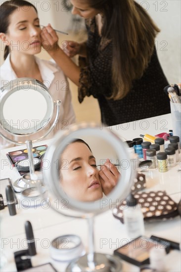 Woman having makeup applied by stylist