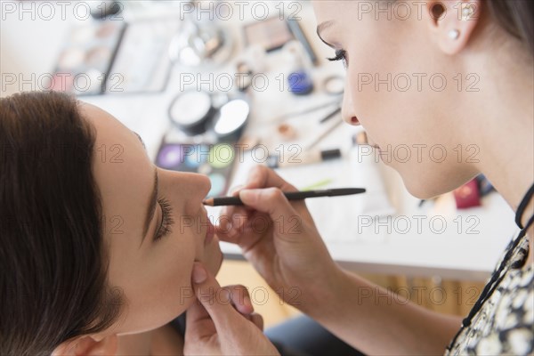 Woman having makeup applied by stylist