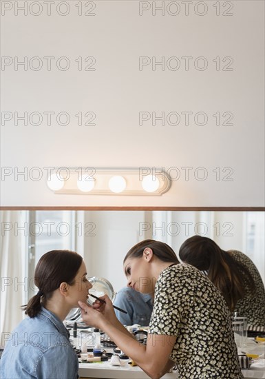 Woman having makeup applied by stylist