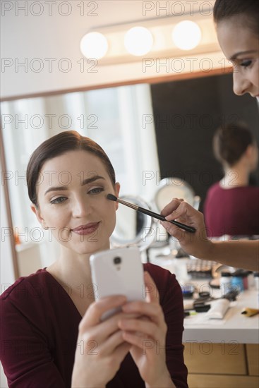 Woman having makeup applied by stylist