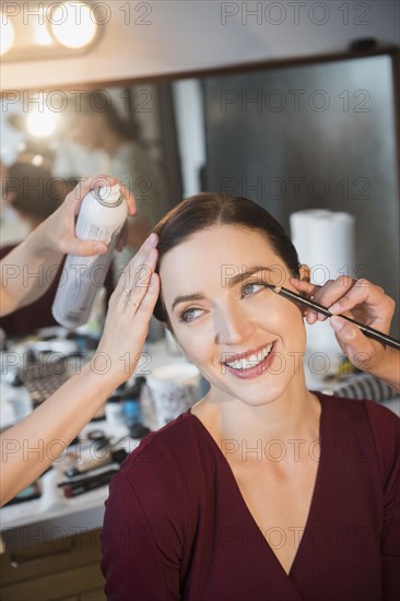 Woman having makeup applied by stylists