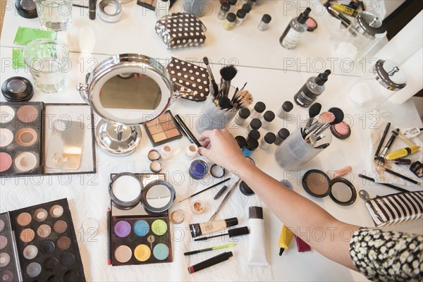 Hispanic woman selecting makeup from table