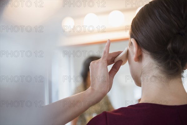 Woman having makeup applied by stylist