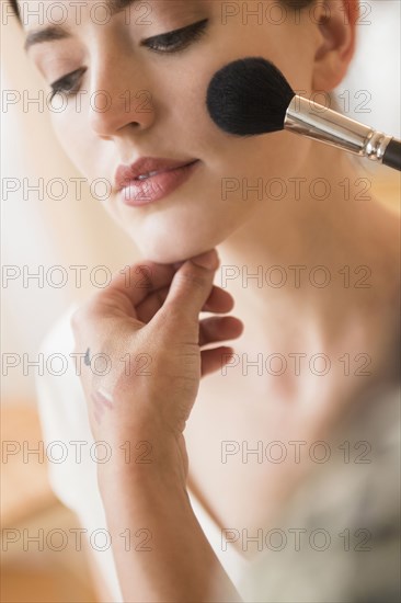 Woman having makeup applied by stylist