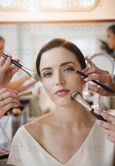 Woman having makeup applied by stylists