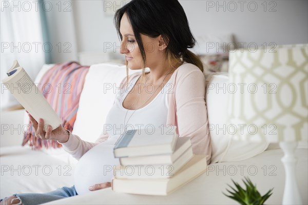 Pregnant Caucasian woman reading baby books