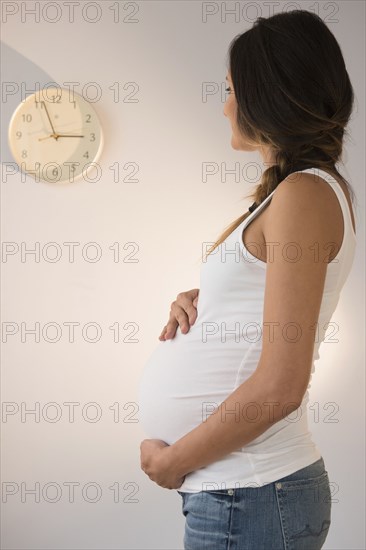 Pregnant Caucasian woman watching clock