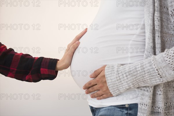 Hand feeling belly of pregnant woman