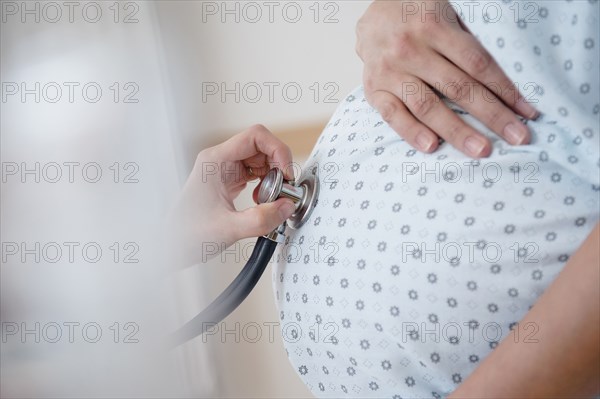 Doctor listening to belly of pregnant woman