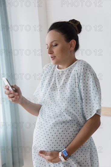 Pregnant Caucasian woman using cell phone in hospital