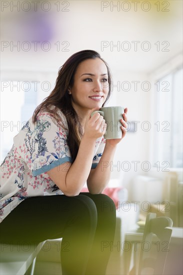 Woman drinking cup of coffee in living room