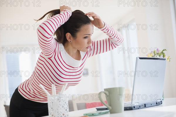 Woman styling her hair with laptop