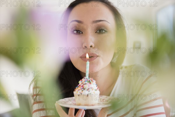 Woman blowing out birthday candle on cupcake