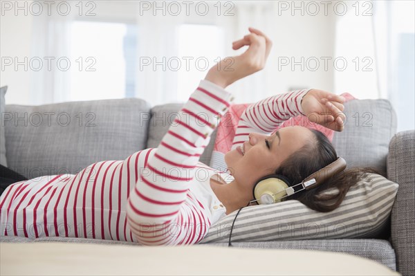 Woman listening to headphones on sofa