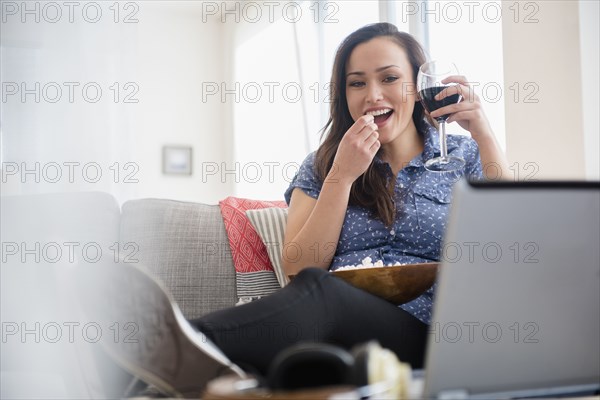 Woman watching movie on laptop in living room