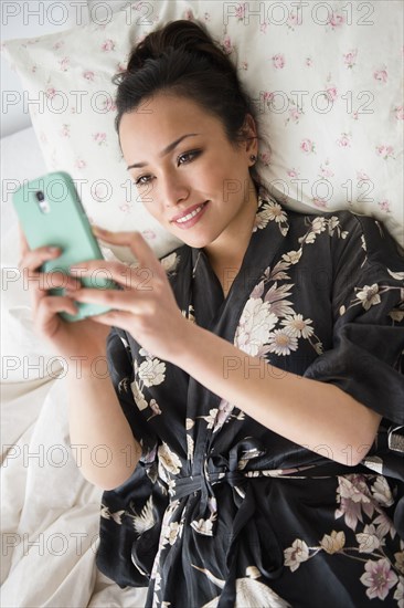 Woman using cell phone on bed