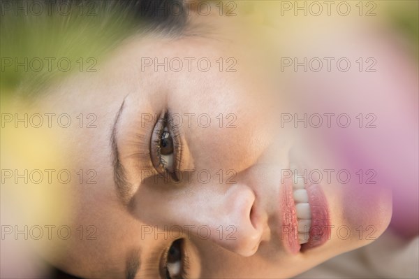 Face of smiling woman obscured by flowers