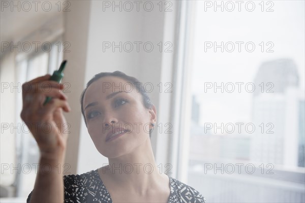 Businesswoman writing on glass wall