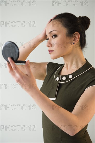Businesswoman checking makeup in compact mirror