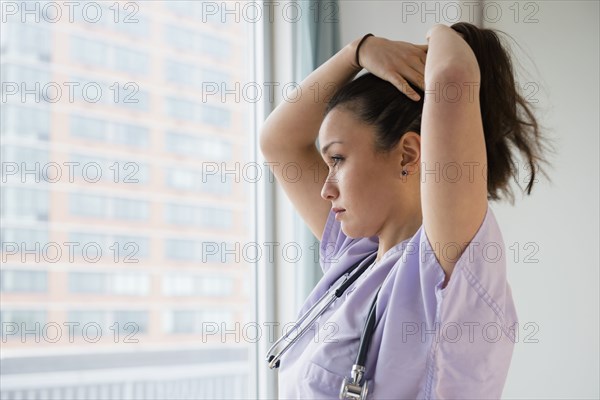 Nurse tying her hair up in hospital