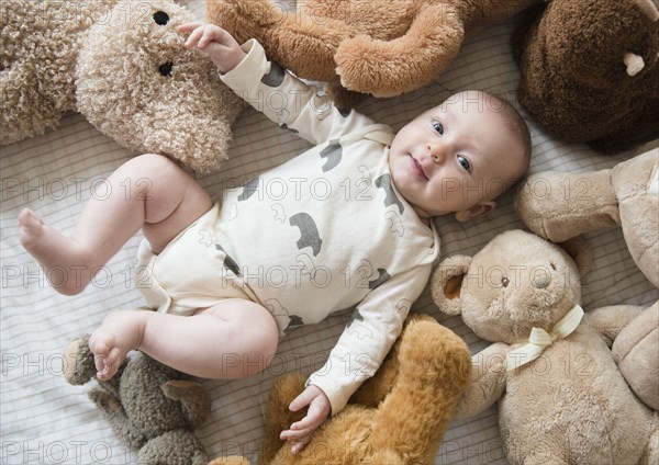 Caucasian baby stuffed animals on bed