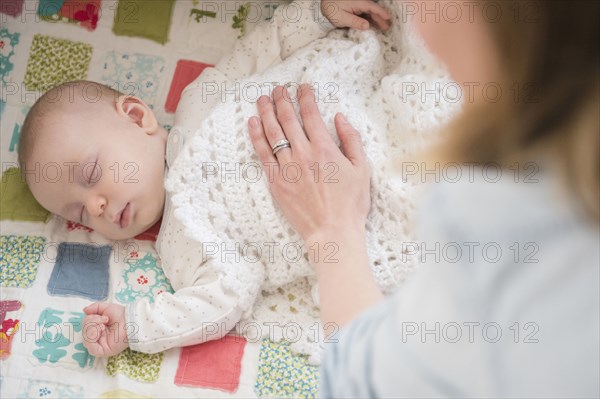 Caucasian mother checking on sleeping baby