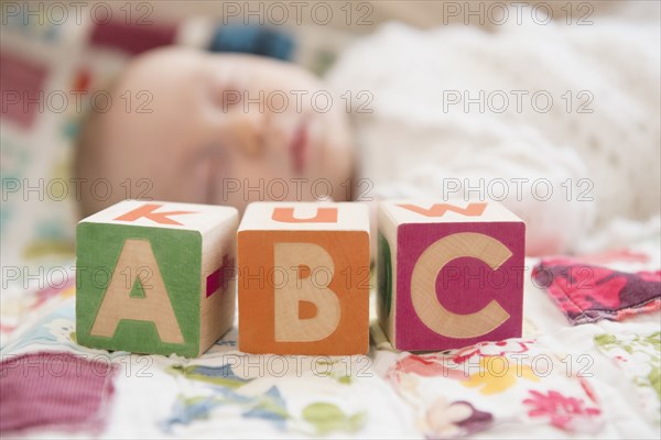 Caucasian baby napping near wooden blocks