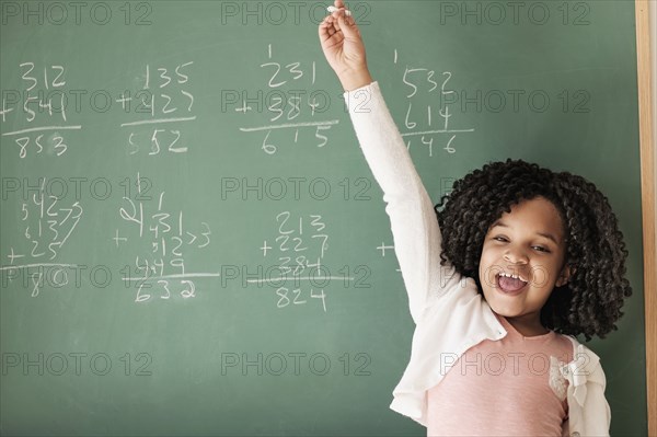 African American student cheering near chalkboard in classroom