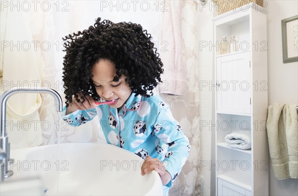 African American girl brushing teeth in bathroom