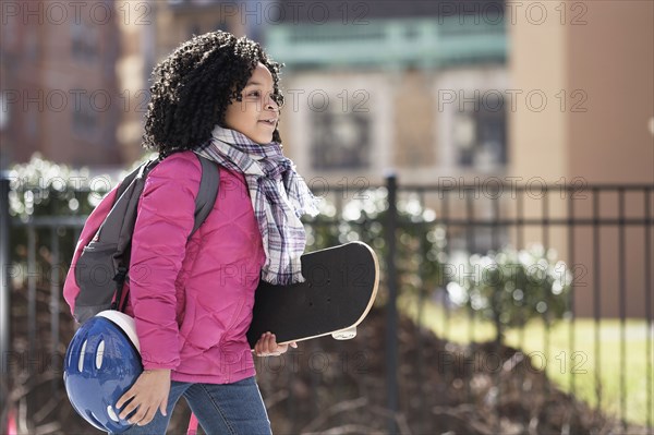African American girl carrying skateboard outdoors