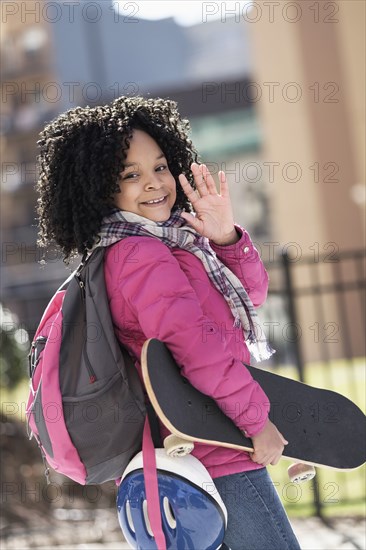 African American girl carrying skateboard outdoors