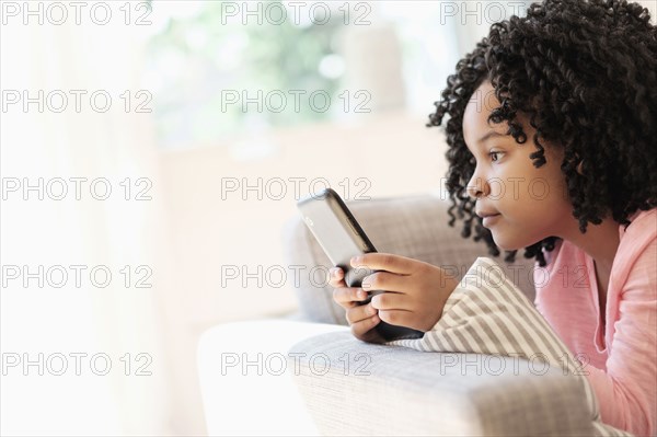 African American girl using cell phone on sofa