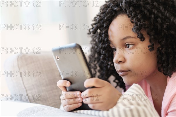 African American girl using cell phone on sofa