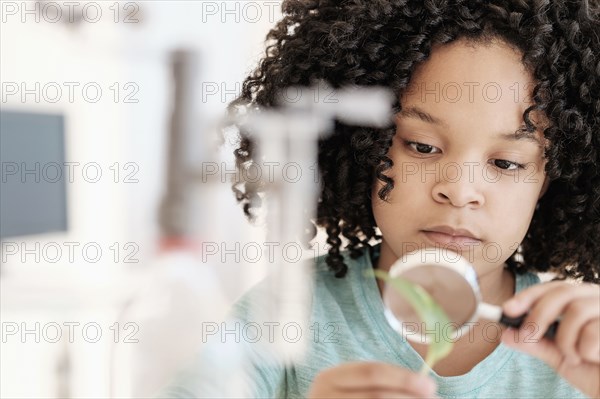 African American girl examining leaf in science classroom