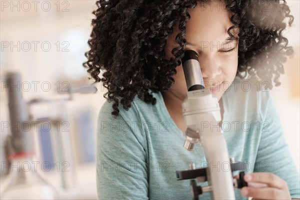 African American girl using microscope in science classroom