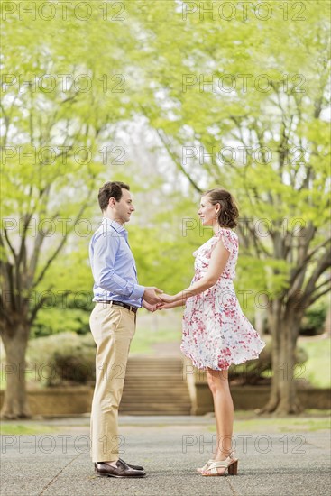 Pregnant Caucasian couple holding hands outdoors