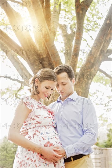 Pregnant Caucasian couple hugging outdoors