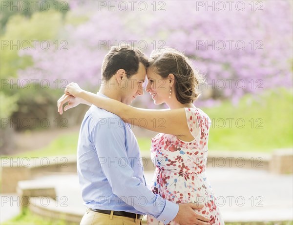 Pregnant Caucasian couple hugging outdoors