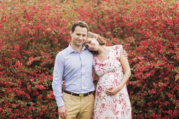 Pregnant Caucasian couple hugging outdoors