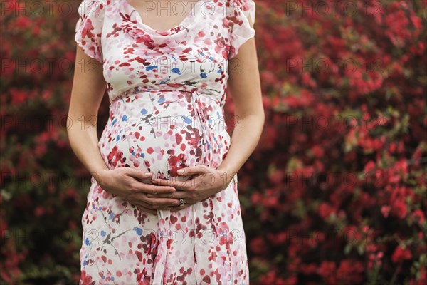 Pregnant Caucasian woman holding her belly outdoors