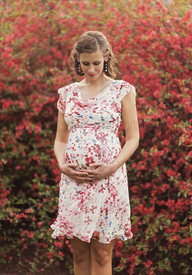 Pregnant Caucasian woman holding her belly outdoors