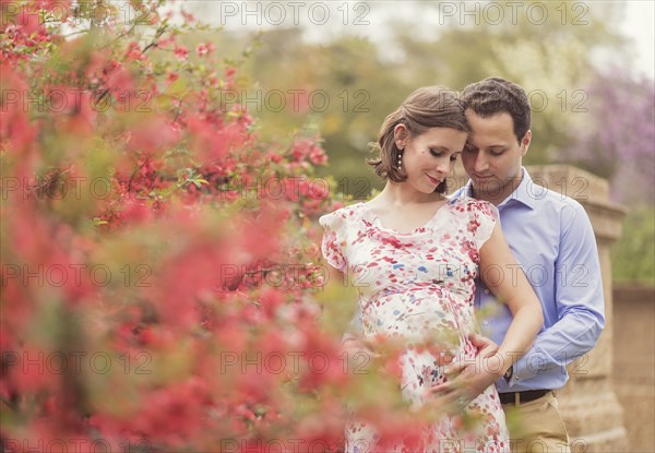 Pregnant Caucasian couple hugging outdoors